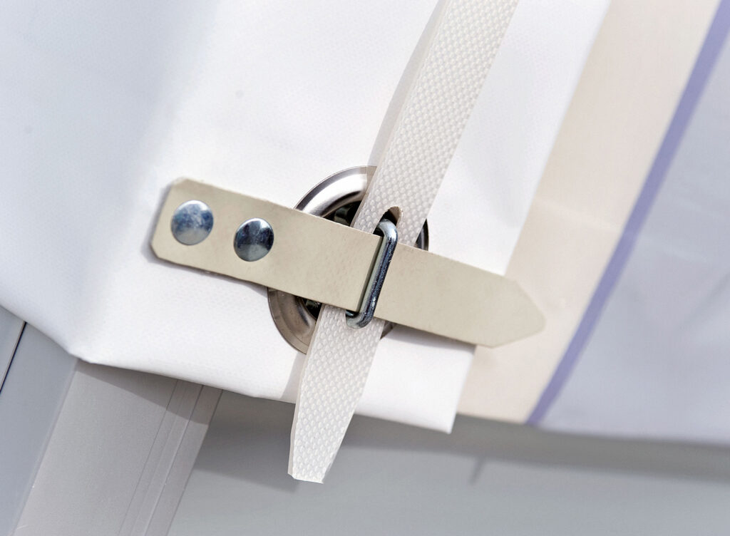 Detailaufnahme einer Plane mit Öse und Spannverschluss.