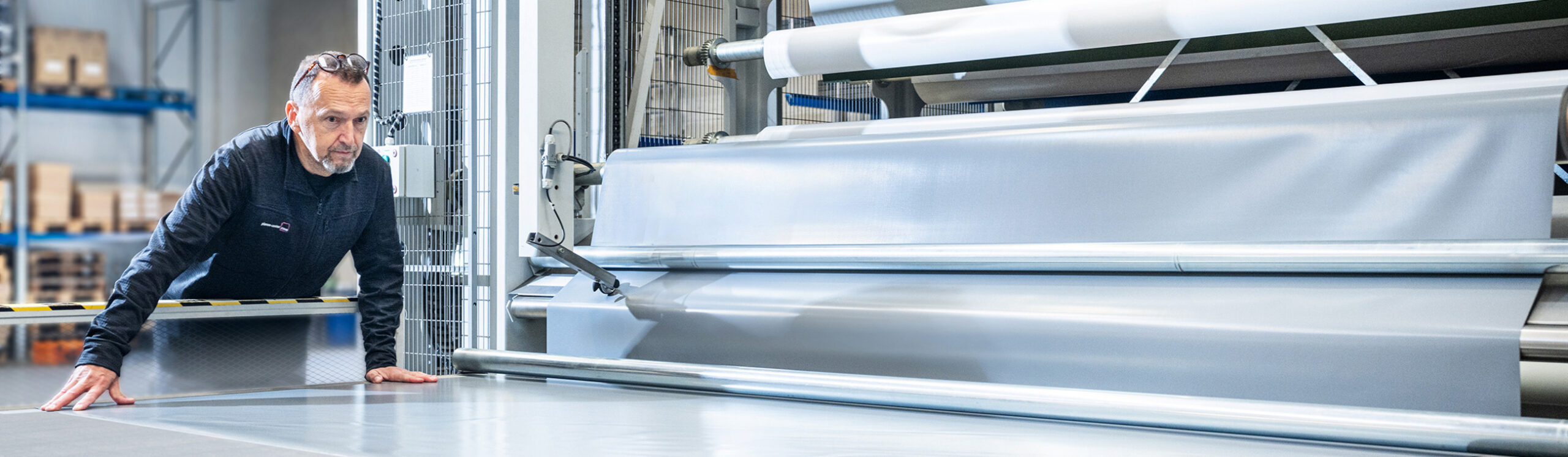 Mitarbeiter bei der Verarbeitung von Planenmaterial an einer Industriemaschine – individuelle Sonderlösungen in der Fertigung.