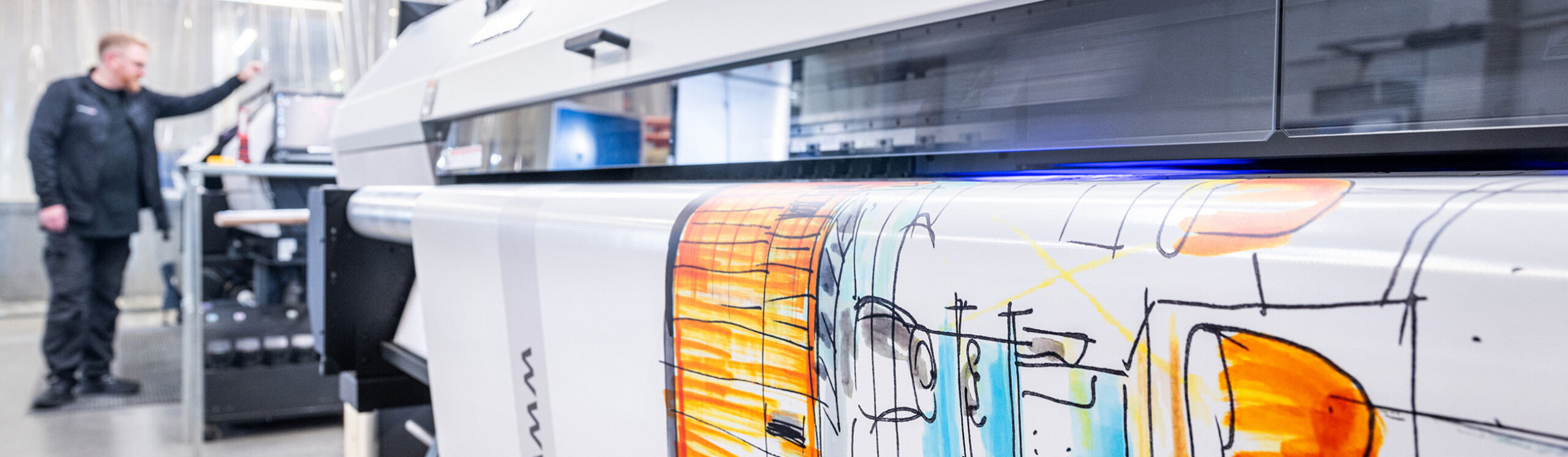 Großformatdrucker im Einsatz beim Druck von farbintensivem Planenmotiv in der Produktion.